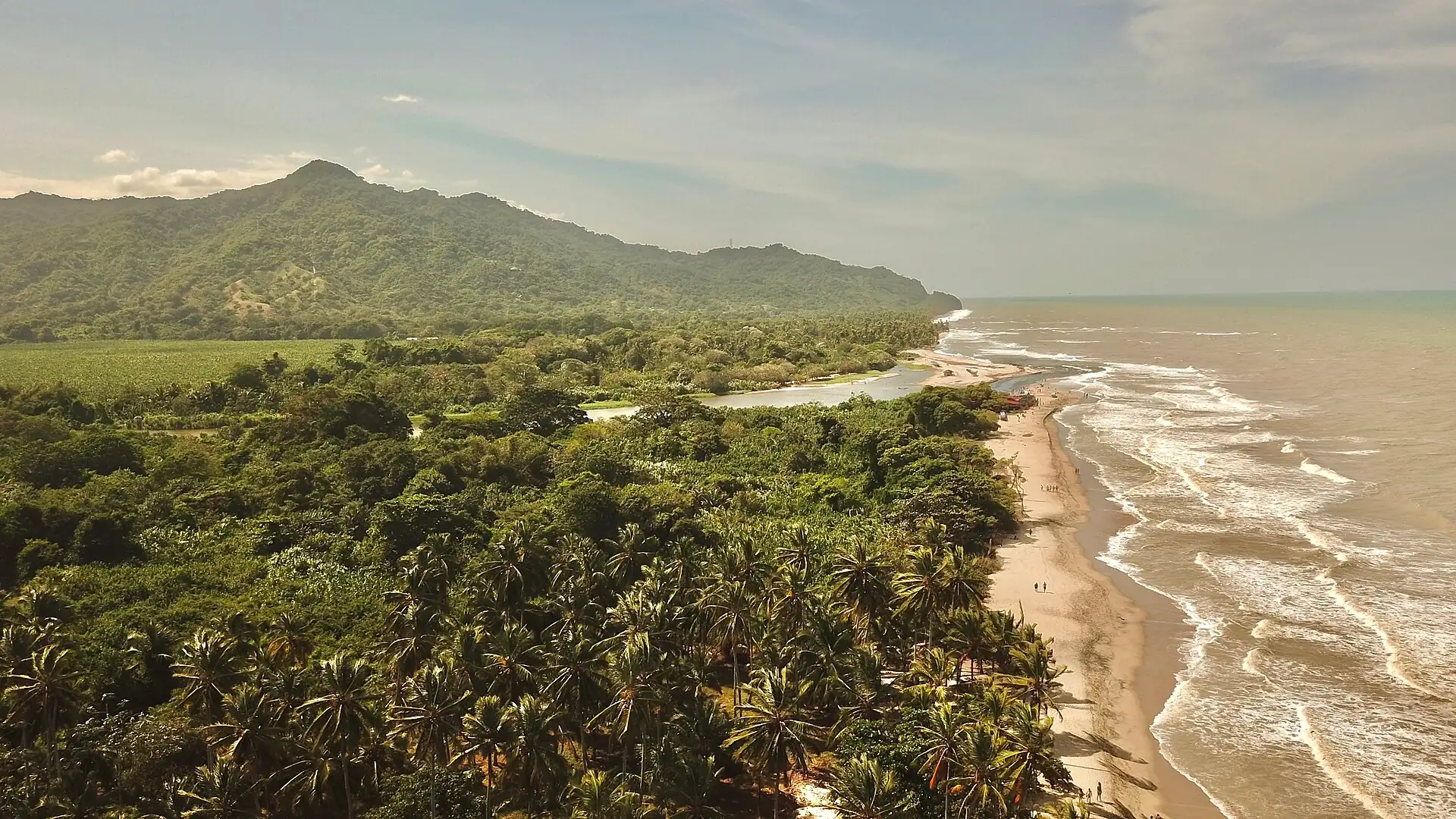 Desembocadura del río Palomino en el mar Caribe, rodeada de selva y con la Sierra Nevada al fondo