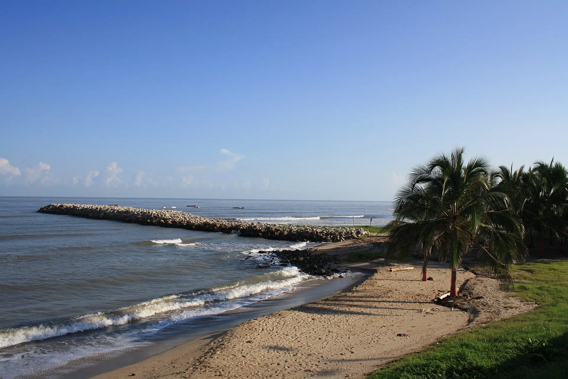 Espolón de piedra y palmeras en la playa de Riohacha en la mañana