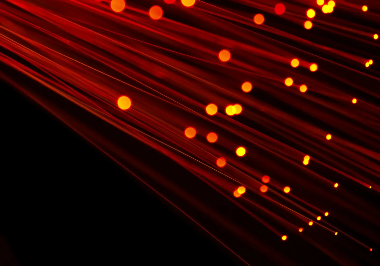Haces de fibra óptica con puntos de luz cálida sobre fondo oscuro