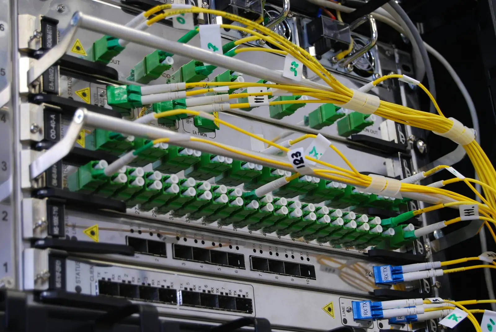 Rack de telecomunicaciones con cables de fibra óptica conectados a un switch